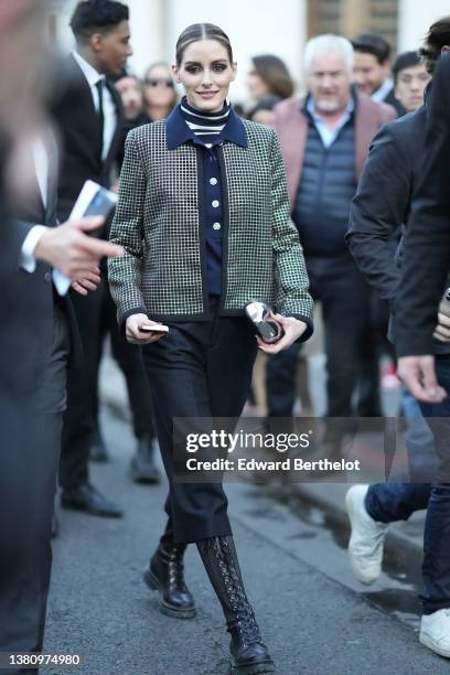 Olivia Palermo wears a black and white print pattern turtleneck pullover, a navy blue with large crystal buttons jacket, a black with embroidered...