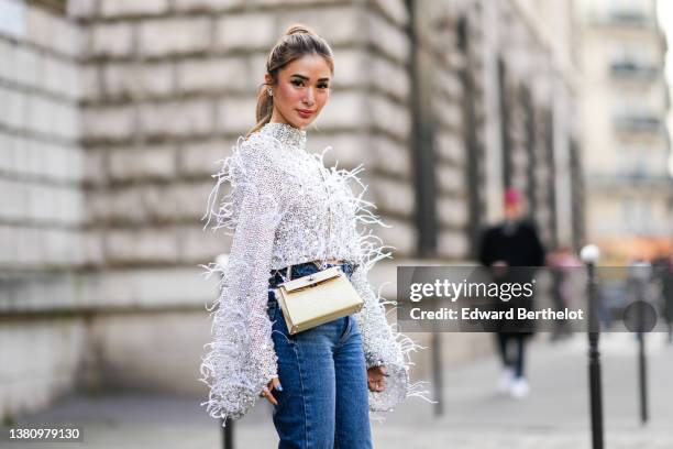 Heart Evangelista wears silver and rhinestones earrings, a gray embroidered crystal and rhinestones with feathers long puffy sleeves high neck...