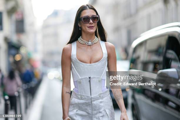 Maeva Marshall wears brown sunglasses, a white pearls large necklaces from Vivienne Westwood, a white V-neck corset tank-top, white pearls bracelets...