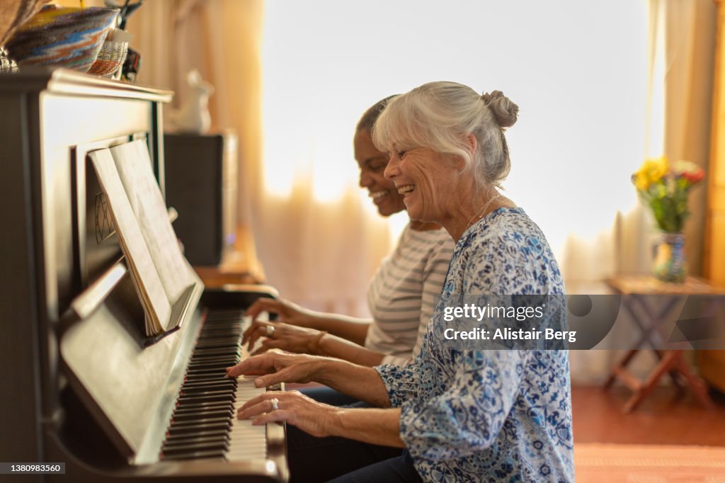Two women playing the piano together at home