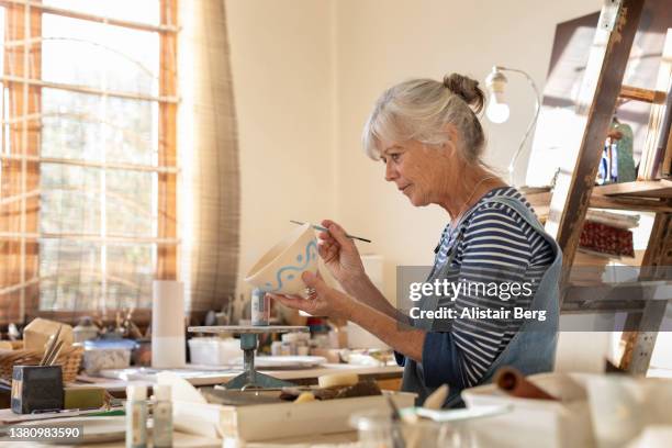 female artist making a clay bowl in her pottery studio - nebenjob stock-fotos und bilder