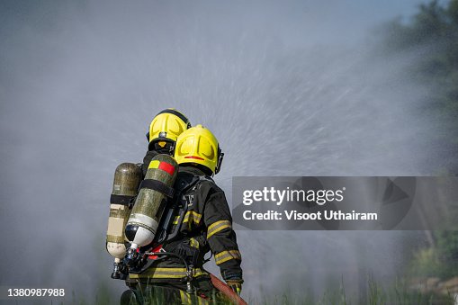 Firefighters fighting fire during training,Firefighter using extinguisher and spray water from hose for fire fighting. Firefighters fighting fire during training,Firefighter using extinguisher and spray water from hose for fire fighting.