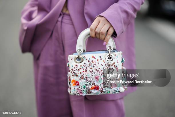 Olga Ferrara wears a pale purple buttoned gilet, a matching pale purple blazer jacket, matching pale purple large pants, a beige leather with...