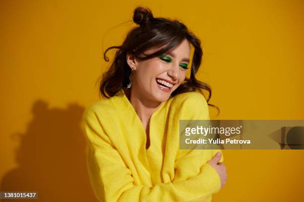 portrait of a beautiful smiling girl with bright makeup and wavy hair on a bright yellow background - eastern european woman fotografías e imágenes de stock