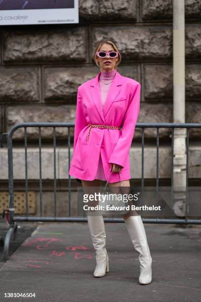 Pauline Guelen wears pink sunglasses, a pale pink turtleneck wool short dress, a white pearls necklace with a silver pendant from Vivienne Westwood,...