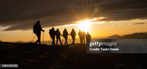 silhouettes of hikers at sunset - people climbing walking mountain group stock pictures, royalty-free photos & images