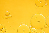 Golden yellow abstract oil bubbles or face serum background.