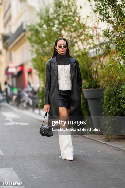 Guest wears black sunglasses, silver heart pendant earrings, a gray glitter / shiny turtleneck pullover, a white lace print pattern laces...