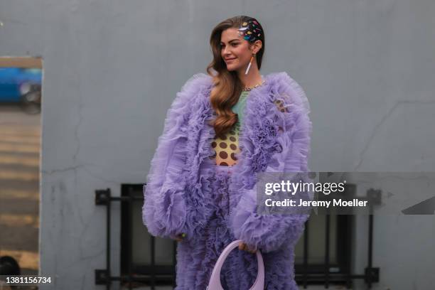 Clara Berry seen wearing colorful hair clips, a green and yellow gradient pattern shirt, a purple oversized ruffled tulle jacket, matching purple...