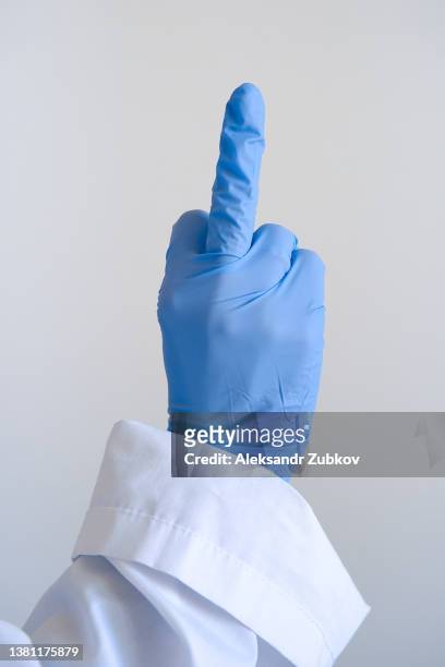 a human hand in blue surgical gloves, showing the middle finger. a doctor or a medical worker shows an aggressive and protesting gesture, the finger will fuck you. - evil doctor stock pictures, royalty-free photos & images