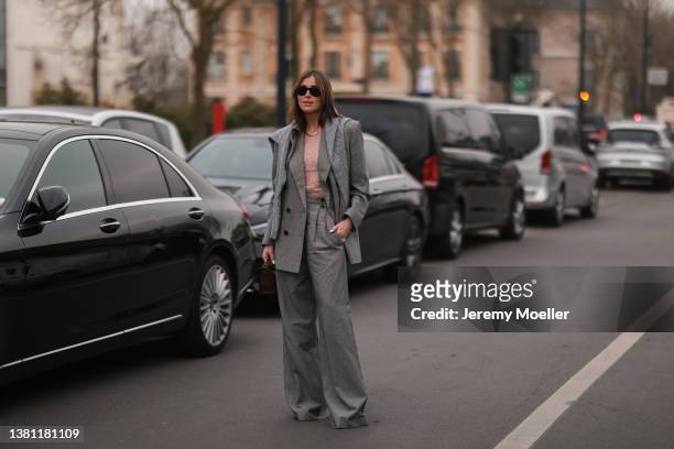 Darja Barannik seen wearing a grey wide leg pants, grey double breasted blazer, a grey pulloverm a black Ray Ban sunglasses and a brown Acne bag on...