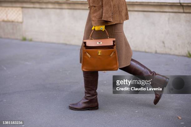 Guest wearing a yellow printed top, brown suede blazer, brown midi skirt, brown boots and camel Hermes bag, is seen outside Hermes, during Paris...