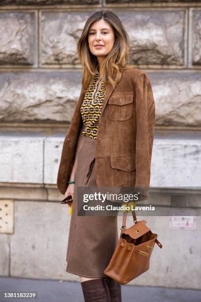 Guest wearing a yellow printed top, brown suede blazer, brown midi skirt, brown boots and camel Hermes bag, is seen outside Hermes, during Paris...