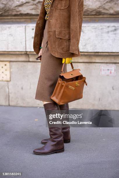 Guest wearing a yellow printed top, brown suede blazer, brown midi skirt, brown boots and camel Hermes bag, is seen outside Hermes, during Paris...