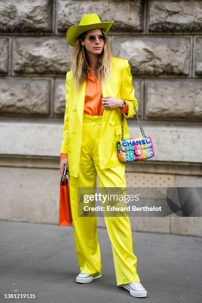 Guest wears a yellow felt / wool cow-boy hat, sunglasses, a pink / blue colored necklace, an orange shirt, a yellow blazer jacket, matching yellow...