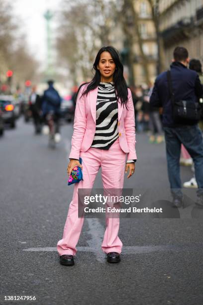 Guest wears a black and white zebra print pattern t-shirt, a pale pink blazer jacket, matching pale pink flared pants, a black bracelet, a blue with...