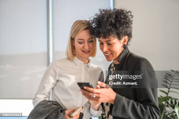 mujeres de negocios de edad mixta que usan teléfonos inteligentes en la oficina moderna - cerca de fotografías e imágenes de stock