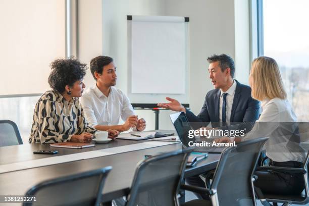 ein japanischer geschäftsmann wendet sich bei einem geschäftstreffen an kollegen - business talk sit men stock-fotos und bilder