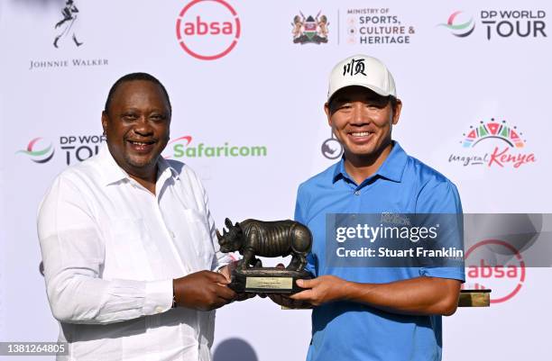 Ashun Wu of China is presented with the Magical Kenya Open trophy by Uhuru Kenyatta, President of Kenya during day four of the Magical Kenya Open at...