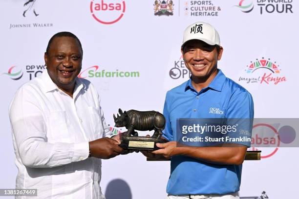 Ashun Wu of China is presented with the Magical Kenya Open trophy by Uhuru Kenyatta, President of Kenya during day four of the Magical Kenya Open at...