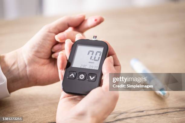 close-up of woman hands measuring glucose level blood test with glucometer. - diabète photos et images de collection