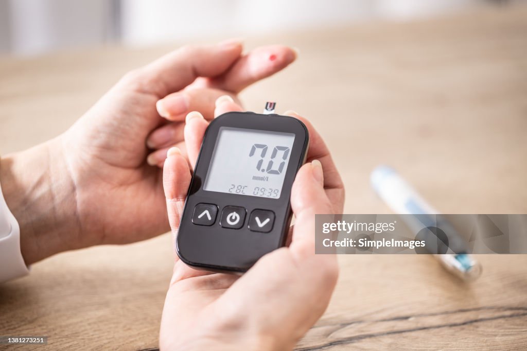 Close-up of woman hands measuring glucose level blood test with glucometer.