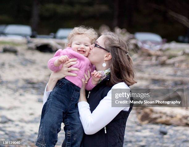 mother kissing her baby girl on beach - sloan stock pictures, royalty-free photos & images