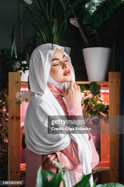 calm tranquil relaxing smiling attractive confident muslim arabian woman in formal elegant white covered head veil hijab. - hijab fashion stockfoto's en -beelden