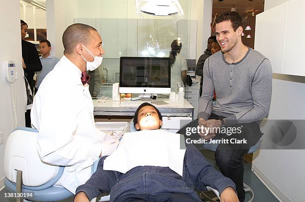 Kris Humphries looks on as Dr. Lee Gause DDS performs dental care on Tariq of Urban Promise during Celebrities For Smiles hosted by Kris Humphries at...