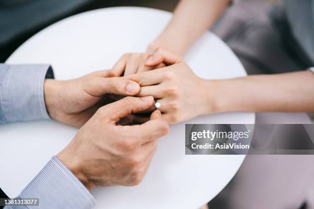 direttamente sopra, inquadratura tagliata di un uomo che mette un anello di fidanzamento al dito della donna. concetto di romanticismo e amore - wedding vows foto e immagini stock