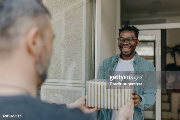 joven afroamericano está encantado de recibir el regalo que ha estado esperando - umbral fotografías e imágenes de stock