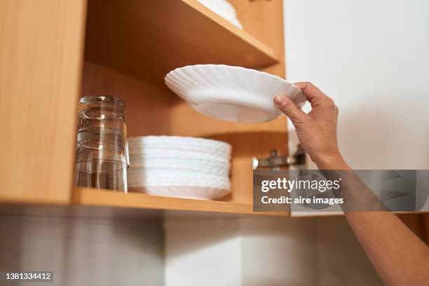 unrecognizable person arranging china dishes in kitchen cabinets, next to crystal glasses. - crystal glasses stockfoto's en -beelden