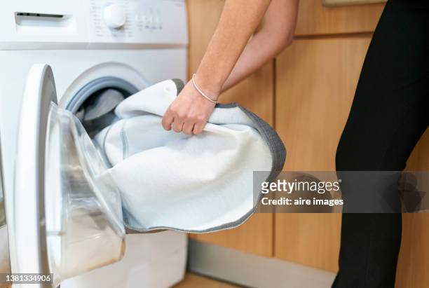 close up photo of female hands taking out clean grey linen from the washing machine. - washing machine photos et images de collection