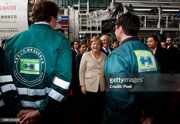 German Chancellor Angela Merkel chats with workers during her visit to a plant of Herrenknecht Tunnelling Equipment Co Ltd on February 3, 2012 in...