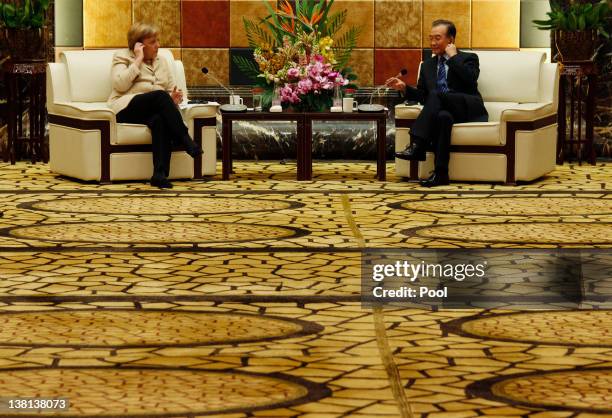 German Chancellor Angela Merkel and Chinese Premier Wen Jiabao adjust their earphones at a meeting with German and Chinese businessmen during their...