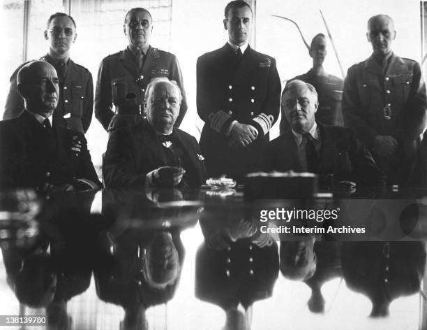 Sitting left to right are Admiral E.J. King , Sir Winston Churchill , and President Franklin D. Roosevelt , while behind them stand, left to right,...