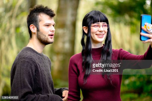 two generation z friends with quirky eccentric style use a cell phone to record a video for tiktok or social media, youth content creation and connectivity - content stock pictures, royalty-free photos & images