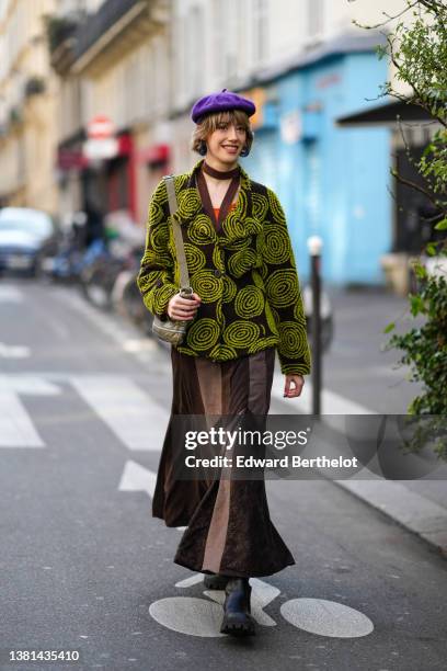 Guest wears a purple wool / felt beret, an orange V-neck tank-top, a dark brown and green print pattern buttoned jacket, a brown cardigan, a khaki...