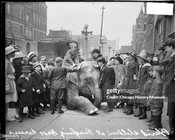 Blind children standing on a sidewalk, one is sitting on the back of a kneeling elephant from the Ringling Brothers Circus, Chicago, Illinois, April...