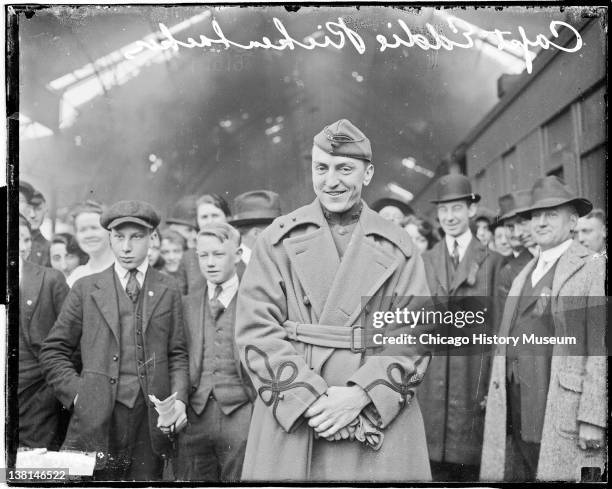 Captain Eddie Rickenbacker standing in a train station with large crowd in background, Chicago, Illinois, 1919.