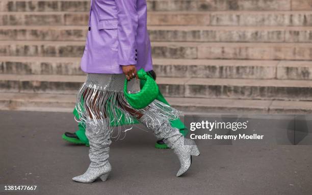 Guest is seen wearing lilac leather blazer, green Bottega Veneta bag, silver skirt with fringes, sparkling knee high boots outside Nanushka...