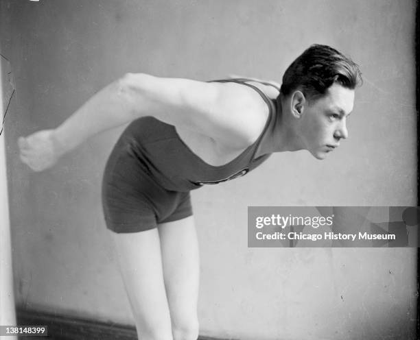 Swimmer John Weissmuller leaning forward, standing in front of a backdrop in a room, Chicago, Illinois, 1922.