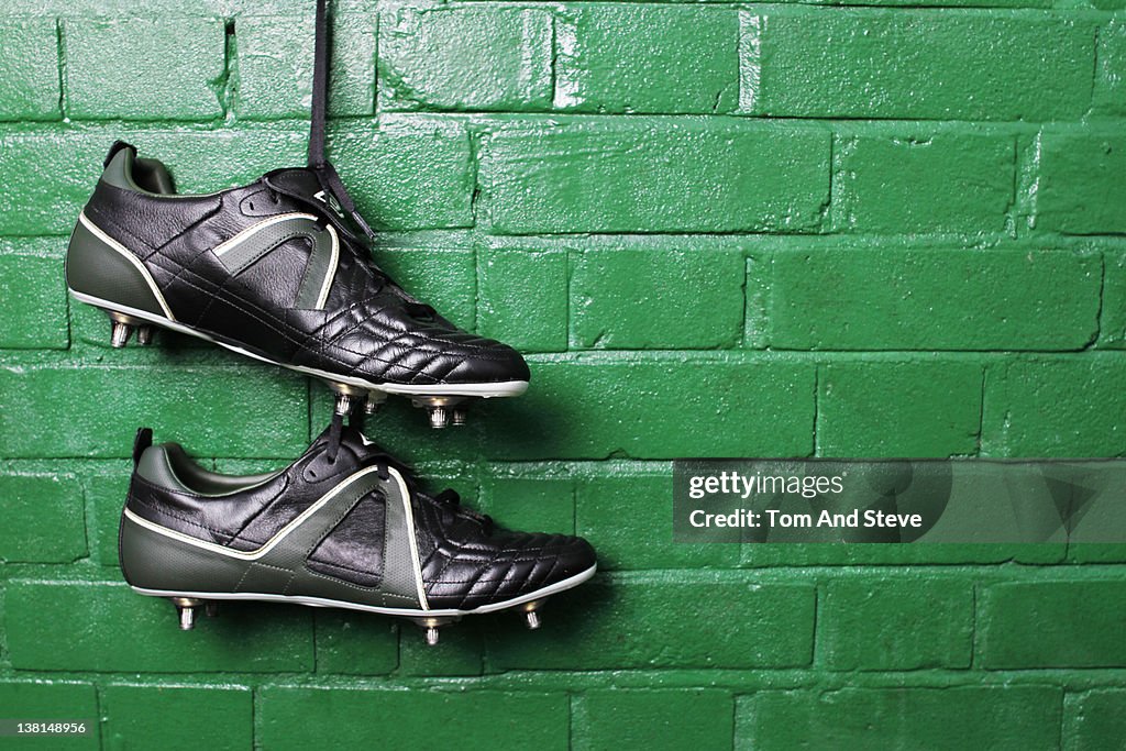 Football boots hanging in changing room wall.