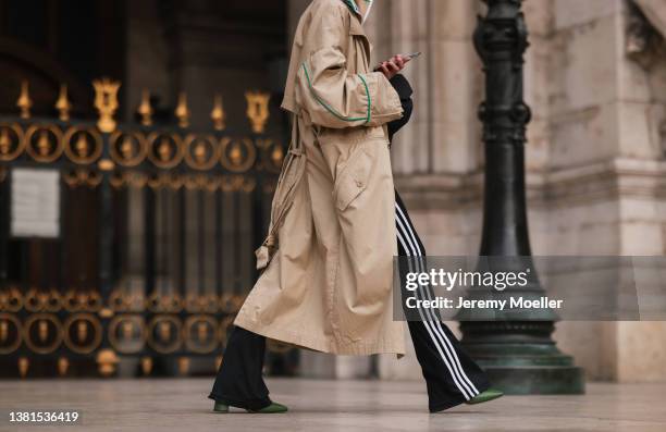 Guest is seen in beige leather trenchcoat and striped flare pants with green ankle boots outside Nanushka presentation, during Paris Fashion Week on...