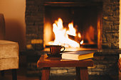 Cup of hot drink in front of warm fireplace