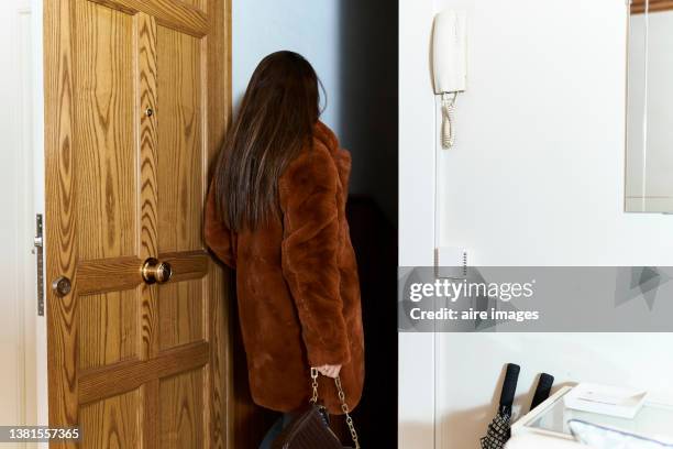 rear view of woman dressed in formal coat and purse leaving home. elegant woman going out to have fun. - abrir a porta sair imagens e fotografias de stock