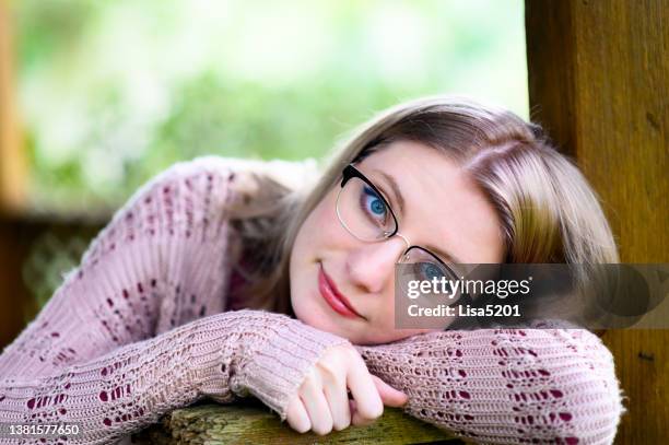 creative relaxed headshot portrait of pretty young generation z woman with glasses and blue eyes outdoors - unhappy woman blonde glasses stock pictures, royalty-free photos & images