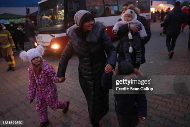 Woman reunited with her grandchildren and daughter after they had arrived from war-torn Ukraine walks with them to her car at the Korczowa shelter...