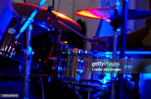 drummer is playing drums in a dimly lit background during a rock concert. - hitting drum stock pictures, royalty-free photos & images