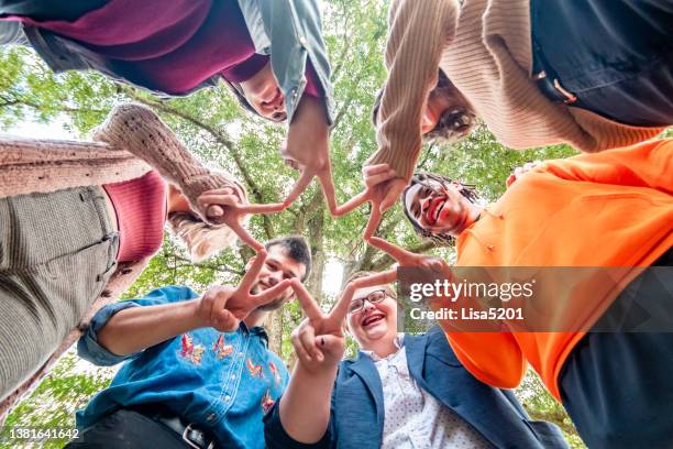 group of young people generation z in a circle form a star with their fingers in a peace sign symbolizing diversity, inclusion, friendship - team building stock pictures, royalty-free photos & images